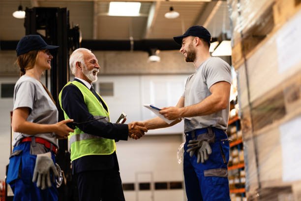 below-view-of-happy-senior-businessman-handshaking-with-warehouse-worker